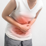 Regl ağrısı çeken orta yaşlı bir kadın, karnını tutarak rahatlama arayışında. Kadın, regl döneminde yaşadığı ağrı nedeniyle karnını sıkarak rahatlama çabası içinde. Orta yaşlı bir kadın, regl ağrılarından kaynaklanan rahatsızlıkla başa çıkmaya çalışırken.